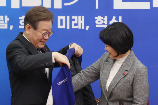 11일 국회에서 열린 더불어민주당 인재영입식에서 이재명 대표가 1호 영입인재인 박지혜 변호사에게 점퍼를 선물하고 있다. 연합뉴스.